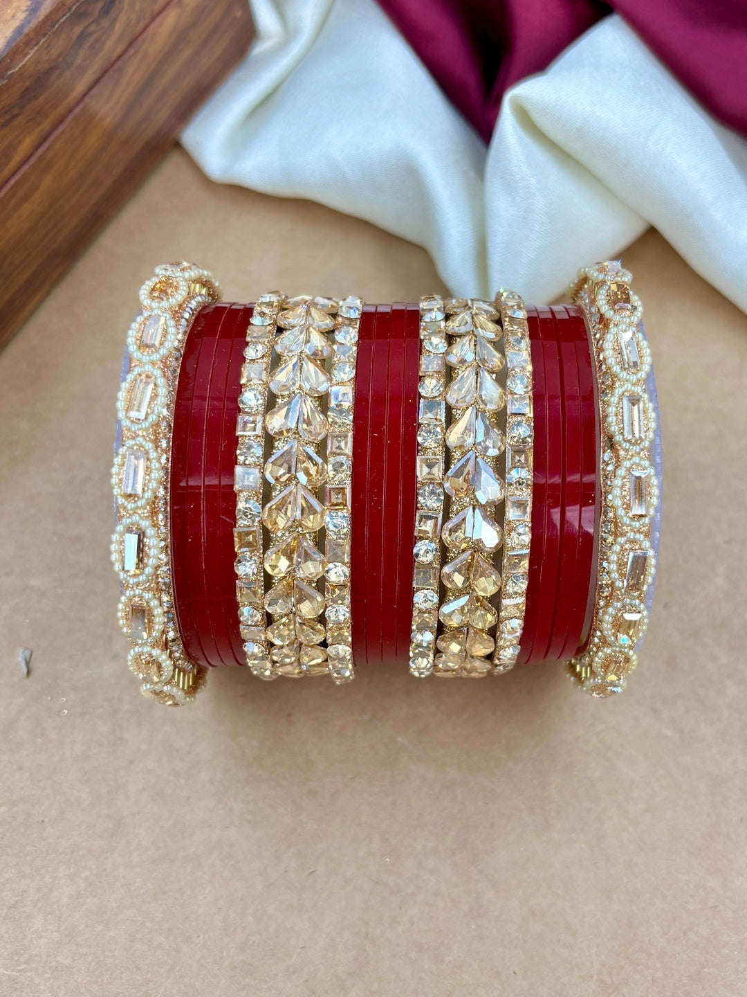 Ishhaara Embellished Red Plastic Bangle Set - A stack of red plastic bangles adorned with intricate Kundan stone and pearl designs