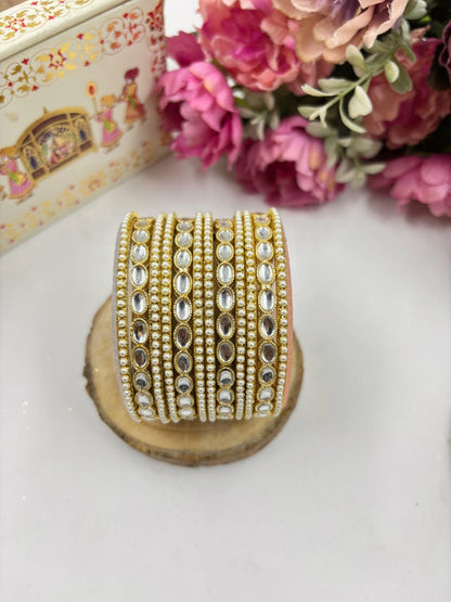 Ishhaara Kundan Gold Bangles - A close-up of intricately designed gold bangles adorned with stones.